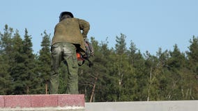 O soldador na roupa de trabalho do special no telhado dobra a máquina de soldadura e move-a para o outro partido para a aplicação video estoque O soldador na roupa de trabalho do special no telhado dobra a máquina de soldadura e move-a para o outro partido para a aplicação video estoque