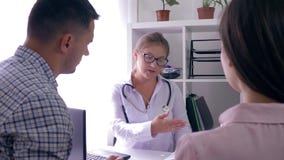 O trabalhador médico diz a boa notícia sobre a saúde de um casal novo no escritório na tabela filme O trabalhador médico diz a boa notícia sobre a saúde de um casal novo no escritório na tabela filme