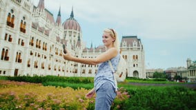 O turista da jovem mulher dá uma volta na perspectiva do parlamento húngaro, toma imagens com si mesma pelo telefone vídeos de arquivo O turista da jovem mulher dá uma volta na perspectiva do parlamento húngaro, toma imagens com si mesma pelo telefone vídeos de arquivo