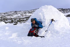O viajante derrama-se uma bebida quente de uma garrafa térmica, sentando-se em um iglu nevado da casa foto de stock O viajante derrama-se uma bebida quente de uma garrafa térmica, sentando-se em um iglu nevado da casa foto de stock