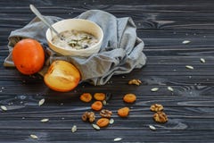 Oatmeal με Persimmon σε έναν μαύρο ξύλινο πίνακα στοκ φωτογραφίες με δικαίωμα ελεύθερης χρήσης Oatmeal με Persimmon σε έναν μαύρο ξύλινο πίνακα στοκ φωτογραφίες με δικαίωμα ελεύθερης χρήσης