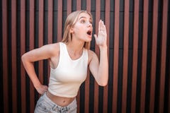 Obrazek dziewczyna w białej koszulowej pozyci w pozyci dzwonić somebody Utrzymuje jej rękę blisko do usta i fotografia royalty free Obrazek dziewczyna w białej koszulowej pozyci w pozyci dzwonić somebody Utrzymuje jej rękę blisko do usta i fotografia royalty free