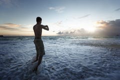 Obsługuje brać fotografie zmierzch na tropikalnej plaży smartphone obraz royalty free Obsługuje brać fotografie zmierzch na tropikalnej plaży smartphone obraz royalty free