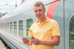 Obsługuje trzymać pastylkę komputerowa blisko pociągu fotografia stock Obsługuje trzymać pastylkę komputerowa blisko pociągu fotografia stock