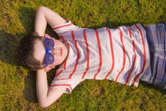 Occhiali da sole di Boywith che prendono il sole sull'erba nell'estate Fotografia Stock Occhiali da sole di Boywith che prendono il sole sull'erba nell'estate Fotografia Stock