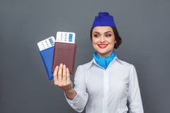 Occupazione professionale Condizione dell'hostess isolata su grigio con i passaporti e sorridere del primo piano dei biglietti em immagini stock Occupazione professionale Condizione dell'hostess isolata su grigio con i passaporti e sorridere del primo piano dei biglietti em immagini stock