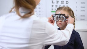 Oculista de visita da estudante pequena bonita para a visão de medição com phoropter vídeos de arquivo Oculista de visita da estudante pequena bonita para a visão de medição com phoropter vídeos de arquivo