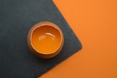 Oeuf ouvert avec le jaune sur le fond orange images stock Oeuf ouvert avec le jaune sur le fond orange images stock