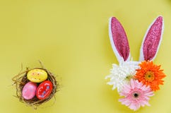 Oeufs de pâques colorés dans un nid et une décoration de lapin d'oreille de lapin de Pâques avec des fleurs de gerbera et de chry photos libres de droits Oeufs de pâques colorés dans un nid et une décoration de lapin d'oreille de lapin de Pâques avec des fleurs de gerbera et de chry photos libres de droits