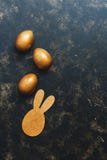 Oeufs et lapin de pâques d'or sur un fond rustique foncé Vue supérieure, configuration plate, l'espace de copie image libre de droits Oeufs et lapin de pâques d'or sur un fond rustique foncé Vue supérieure, configuration plate, l'espace de copie image libre de droits