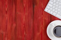 Office desk with copy space. Digital devices wireless keyboard and mouse on red wooden table with cup of coffee, top view royalty free stock photo Office desk with copy space. Digital devices wireless keyboard and mouse on red wooden table with cup of coffee, top view royalty free stock photo