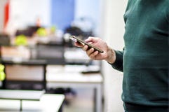The office employee uses a modern smartphone in the background of the office. The employee of the corporation stock image The office employee uses a modern smartphone in the background of the office. The employee of the corporation stock image