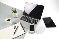 Office table with laptop computer, notebook, digital tablet and smartphone on modern two tone white and grey background Royalty Free Stock Images Office table with laptop computer, notebook, digital tablet and smartphone on modern two tone white and grey background Royalty Free Stock Images