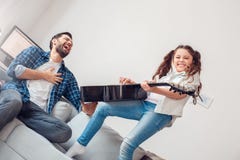 Ojciec i mała córki dziewczyna bawić się gitarę rozochoconą w domu podczas gdy ojca śmiać się obrazy stock Ojciec i mała córki dziewczyna bawić się gitarę rozochoconą w domu podczas gdy ojca śmiać się obrazy stock
