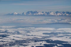 Ojämna snöig höga Tatra maxima ovanför den disiga Podhale handfatet Polen arkivfoto Ojämna snöig höga Tatra maxima ovanför den disiga Podhale handfatet Polen arkivfoto