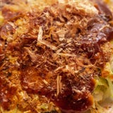 Okonomiyaki - Japanese pancake with bacon and cabbage, a spicy sauce and sprinkled with Bonito royalty free stock image Okonomiyaki - Japanese pancake with bacon and cabbage, a spicy sauce and sprinkled with Bonito royalty free stock image