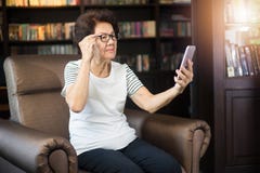 Old asian woman looking at smartphone screen. Royalty Free Stock Image Old asian woman looking at smartphone screen. Royalty Free Stock Image