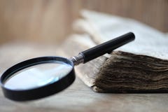 Old books on a wooden table and magnifier