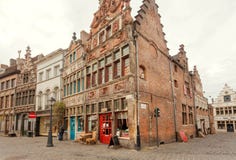 Old brick house with reliefs on wall and small store with red door with customers royalty free stock image Old brick house with reliefs on wall and small store with red door with customers royalty free stock image
