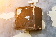 The old electric shield hangs on the exfoliating wall of the house, a rusty metal box hanging on the wall royalty free stock image The old electric shield hangs on the exfoliating wall of the house, a rusty metal box hanging on the wall royalty free stock image