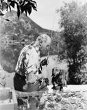 Old man fishing with small dog Stock Images Old man fishing with small dog Stock Images