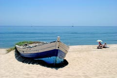 Old rowing boat on sunny white sandy beach