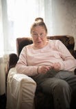 An old smiling woman in glasses sitting in the armchair and knitting. Looking amazedly at somebody stock photos An old smiling woman in glasses sitting in the armchair and knitting. Looking amazedly at somebody stock photos