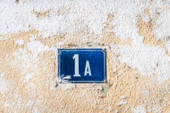 Old vintage house address blue metal number 1 A one on the plaster facade of abandoned home exterior wall on the street side stock image Old vintage house address blue metal number 1 A one on the plaster facade of abandoned home exterior wall on the street side stock image