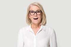 Old woman in glasses sincerely surprised looking at camera