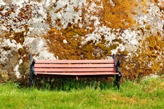 Old wooden bench on green grass near the moss covered stone stock images Old wooden bench on green grass near the moss covered stone stock images
