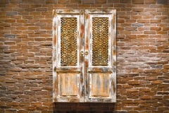 Decorative hanging door on brick wall. Wooden window on brick wall background. Vintage old wooden door exterior. Old