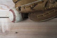 Old worn leather baseball glove and used ball on a wooden Stock Photos Old worn leather baseball glove and used ball on a wooden Stock Photos