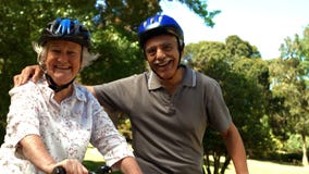 Older couple riding bikes in park