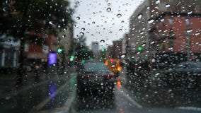 Olhando o tráfego através de um para-brisa coberto com os pingos de chuva, em um dia aborrecido e sombrio imagens de stock Olhando o tráfego através de um para-brisa coberto com os pingos de chuva, em um dia aborrecido e sombrio imagens de stock