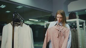 Olhar da compra da mulher sobre vestidos em ganchos na loja do boutique da roupa elegante video estoque Olhar da compra da mulher sobre vestidos em ganchos na loja do boutique da roupa elegante video estoque