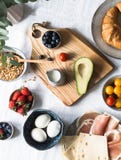 Olika ingredienser för en omväxlande frukostost, prosciuttoen, körsbärsröda tomater, avokadot, ägg, granola, mjölkar, bär som är arkivfoto Olika ingredienser för en omväxlande frukostost, prosciuttoen, körsbärsröda tomater, avokadot, ägg, granola, mjölkar, bär som är arkivfoto