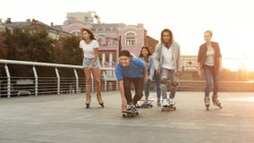 Olika tonåriga vänner som rider på skateboarder och rullar arkivfoton Olika tonåriga vänner som rider på skateboarder och rullar arkivfoton