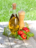Olive oil bottle, pepper shaker, basil and ripe tomatoes. On wooden table Stock Photography Olive oil bottle, pepper shaker, basil and ripe tomatoes. On wooden table Stock Photography