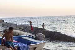 OLUDENIZ - FETHIYE, TURKIJE - 24 AUGUSTUS 2018 De schone spruit van een jongen zit op het zeil in de zonsondergangtijd royalty-vrije stock fotografie OLUDENIZ - FETHIYE, TURKIJE - 24 AUGUSTUS 2018 De schone spruit van een jongen zit op het zeil in de zonsondergangtijd royalty-vrije stock fotografie