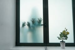 Ombre vaghe di due bambini di orrore Le mani sul vetro Gente pericolosa dietro vetro glassato La gente di mistero Halloween fotografia stock Ombre vaghe di due bambini di orrore Le mani sul vetro Gente pericolosa dietro vetro glassato La gente di mistero Halloween fotografia stock