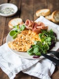 Omelette ou bousculade avec le sésame, la laitue de maïs, le prosciutto du plat blanc et les croûtons sur le fond en bois photo stock Omelette ou bousculade avec le sésame, la laitue de maïs, le prosciutto du plat blanc et les croûtons sur le fond en bois photo stock