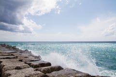 Onde che si schiantano sul frangiflutti davanti ad un cielo blu Immagine Stock Onde che si schiantano sul frangiflutti davanti ad un cielo blu Immagine Stock