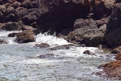 Onde del mare che spruzzano contro le rocce e che entrano in caverna della roccia fotografia stock libera da diritti Onde del mare che spruzzano contro le rocce e che entrano in caverna della roccia fotografia stock libera da diritti