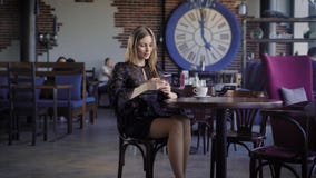 Onderneemster die in zwarte kleding middagpauze van zitting in koffie met mensen in de moderne achtergrond en gebruiken genieten stock videobeelden Onderneemster die in zwarte kleding middagpauze van zitting in koffie met mensen in de moderne achtergrond en gebruiken genieten stock videobeelden