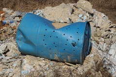 Blue old rumpled plastic barrel lies on a pile of garbage on the street stock photo Blue old rumpled plastic barrel lies on a pile of garbage on the street stock photo