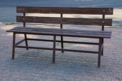 One brown wooden bench stands on a gray sidewalk outside stock photos One brown wooden bench stands on a gray sidewalk outside stock photos