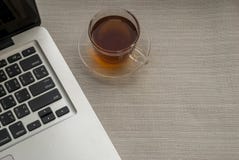 One cup of tea is on the right side of the laptop stock image One cup of tea is on the right side of the laptop stock image