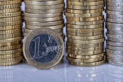 A one euro coin in front of many more coins stacked in columns o stock images A one euro coin in front of many more coins stacked in columns o stock images