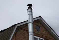 Gray long metal pipe chimney on a brown brick loft against the sky royalty free stock image Gray long metal pipe chimney on a brown brick loft against the sky royalty free stock image