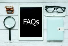 Online digital FAQs Frequently Asked Questions concept. Top view of magnifying glass,notebook,pen,glasses and tablet written with royalty free stock photography Online digital FAQs Frequently Asked Questions concept. Top view of magnifying glass,notebook,pen,glasses and tablet written with royalty free stock photography
